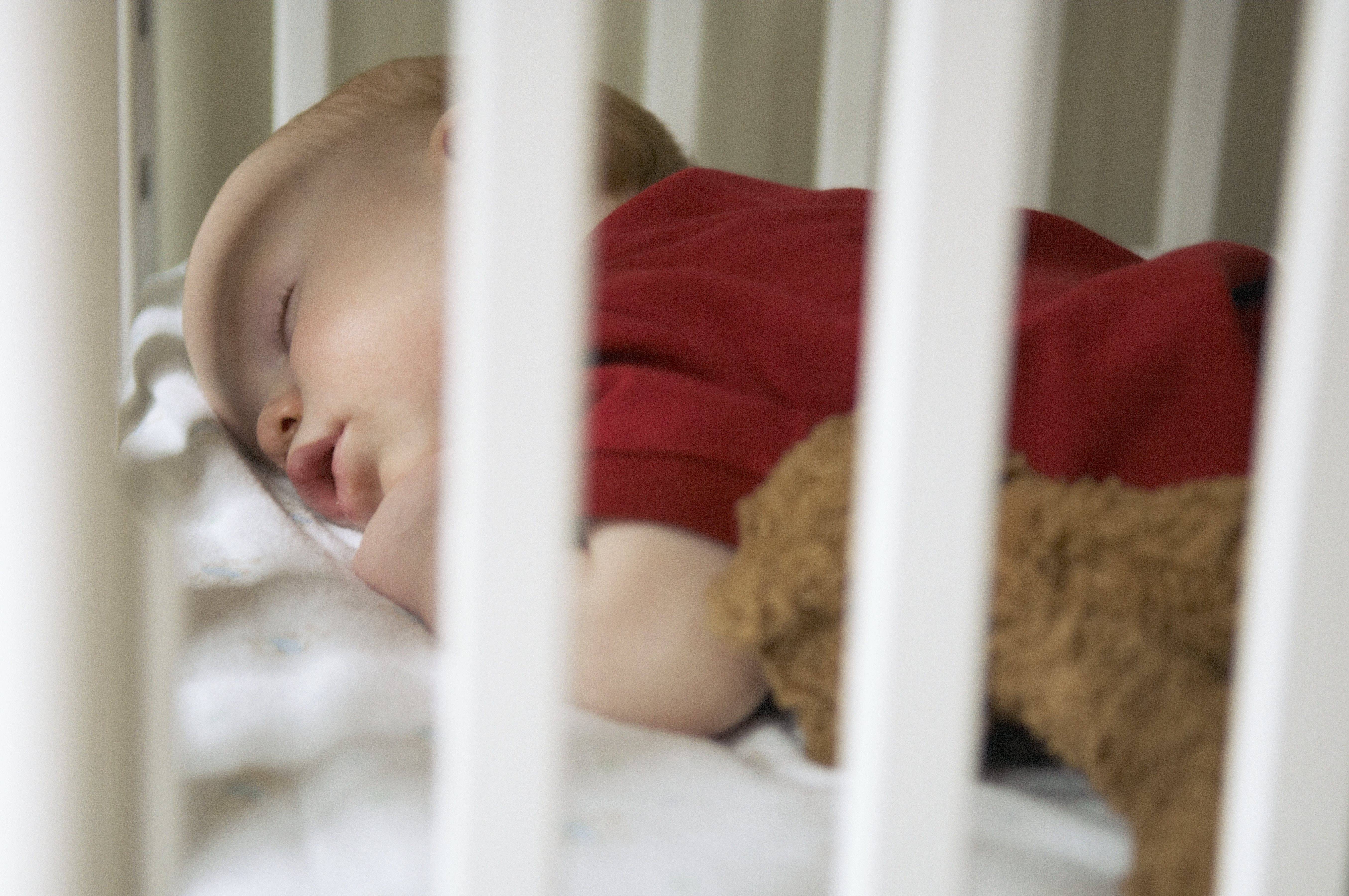 Ребенок спит в детской кроватке