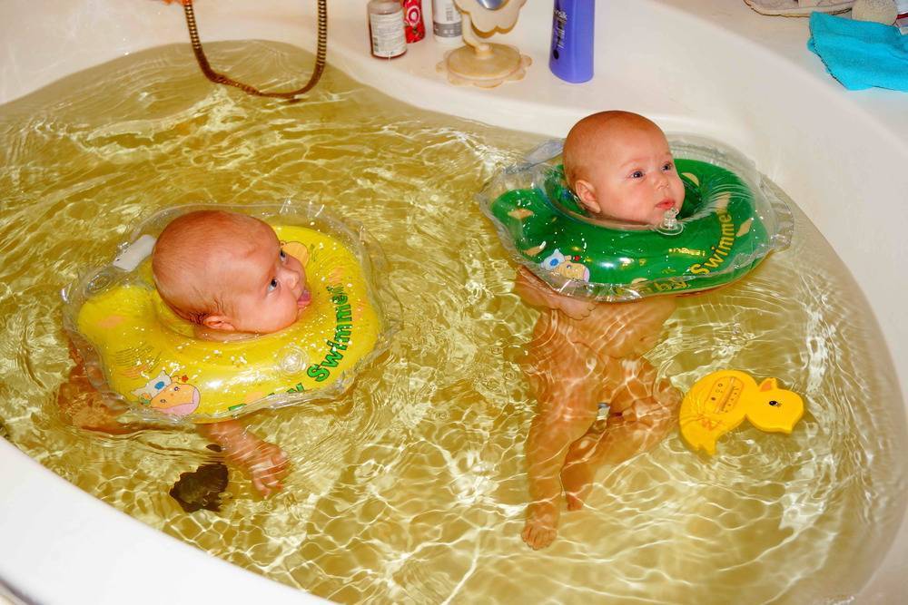Новорожденный купается. Круг для малышей для купания в ванной. Купание грудничка. Купание ребенка с кругом на шее. Ванна для грудных детей.
